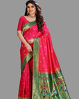 Woman wearing a pink and green paithani saree with a floral background