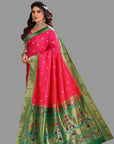 Woman wearing a pink and green paithani saree with a floral pattern on a gray background