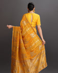 Woman wearing a yellow saree with a dark background