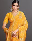 Woman wearing a yellow saree with intricate designs on a gray background