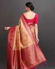 Woman wearing a red and beige saree with a plain background