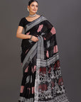 Woman wearing a black saree with pink and white patterns on a gray background