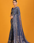 Woman wearing a blue saree with a gold border on an orange background