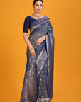 Woman wearing a blue saree with a gold border on an orange background