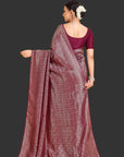 Woman wearing a maroon saree with a purple blouse against an orange background