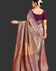 Woman wearing a gold saree with a purple blouse against an orange background