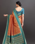 Woman wearing a traditional saree with a blue blouse against a gray background