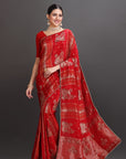 Woman wearing a red saree with gold patterns on a gray background