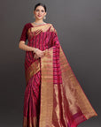 Woman wearing a maroon and gold saree on a gray background
