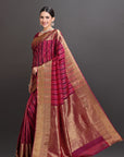 Woman wearing a traditional saree with a maroon and gold pattern on a dark background