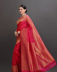 Woman wearing a red saree with a gold border on a gray background