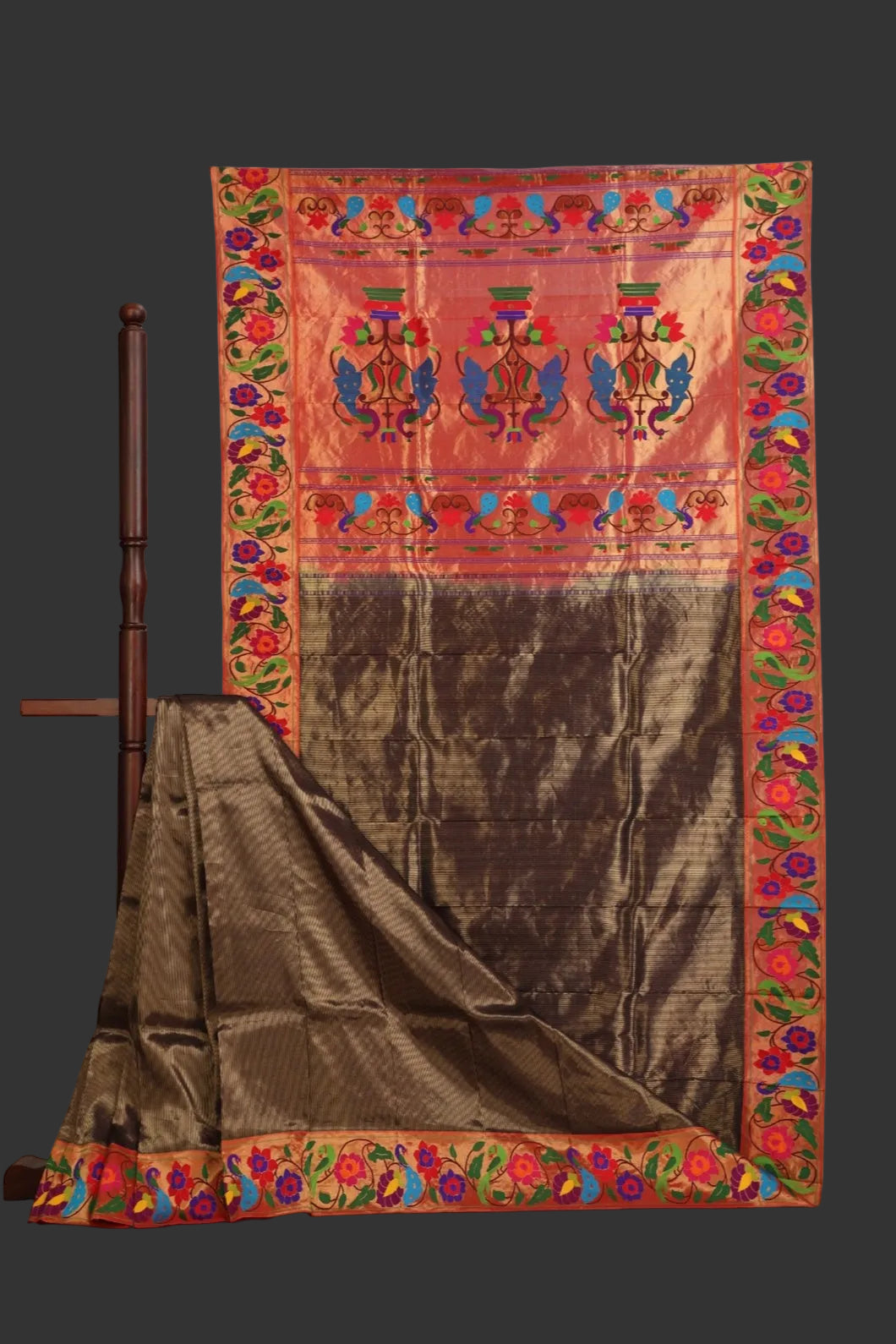 Traditional fabric with intricate patterns on a wooden stand against a white background