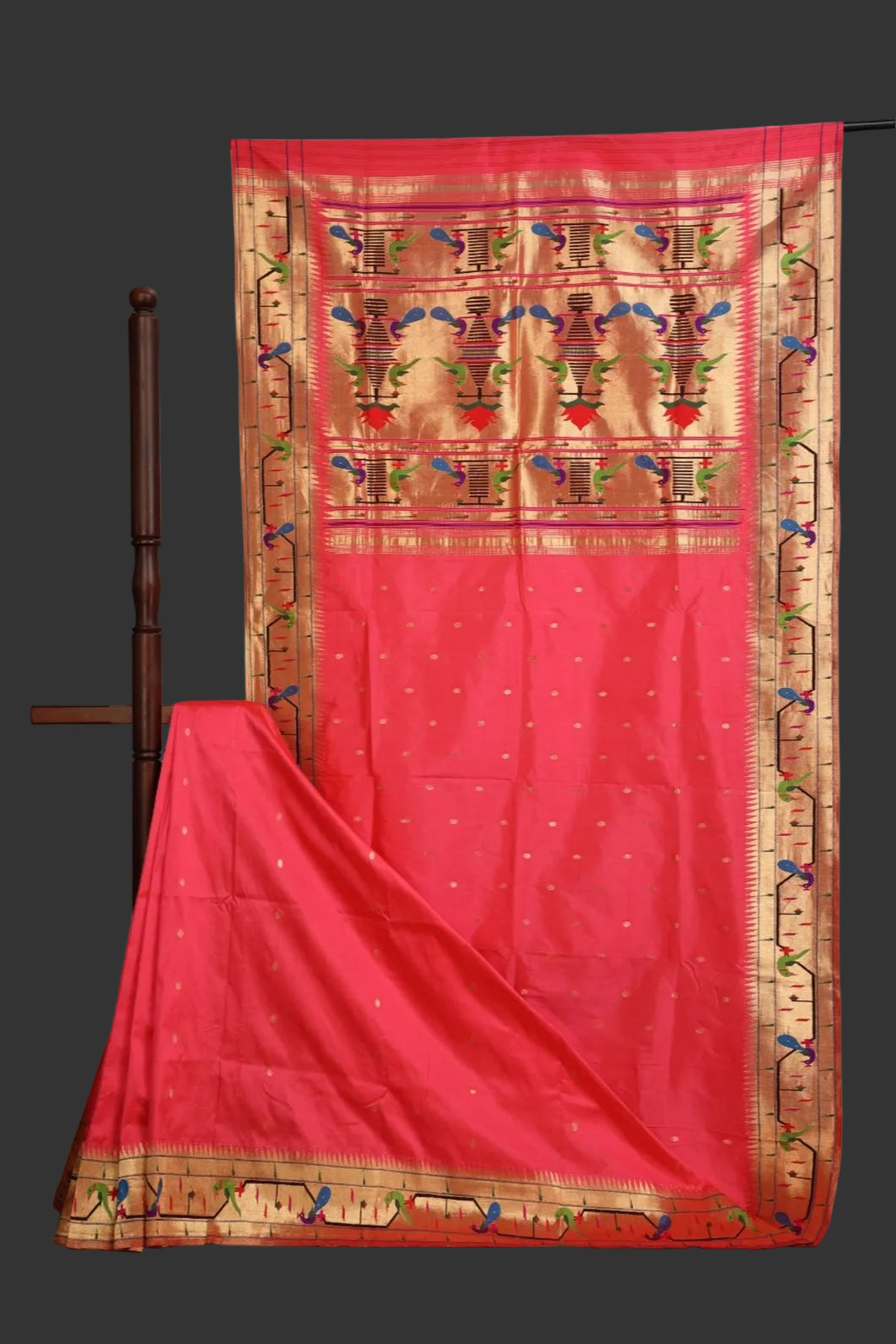 Red saree with gold and multicolor border on a grey background