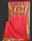 Red saree with gold and multicolor border on a grey background