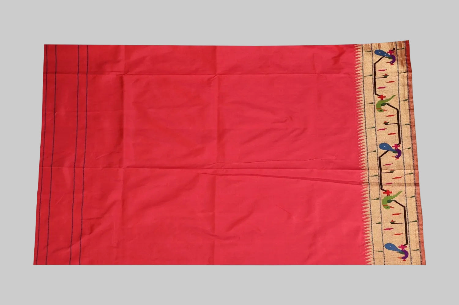 Red fabric with a decorative border featuring colorful patterns on a white background