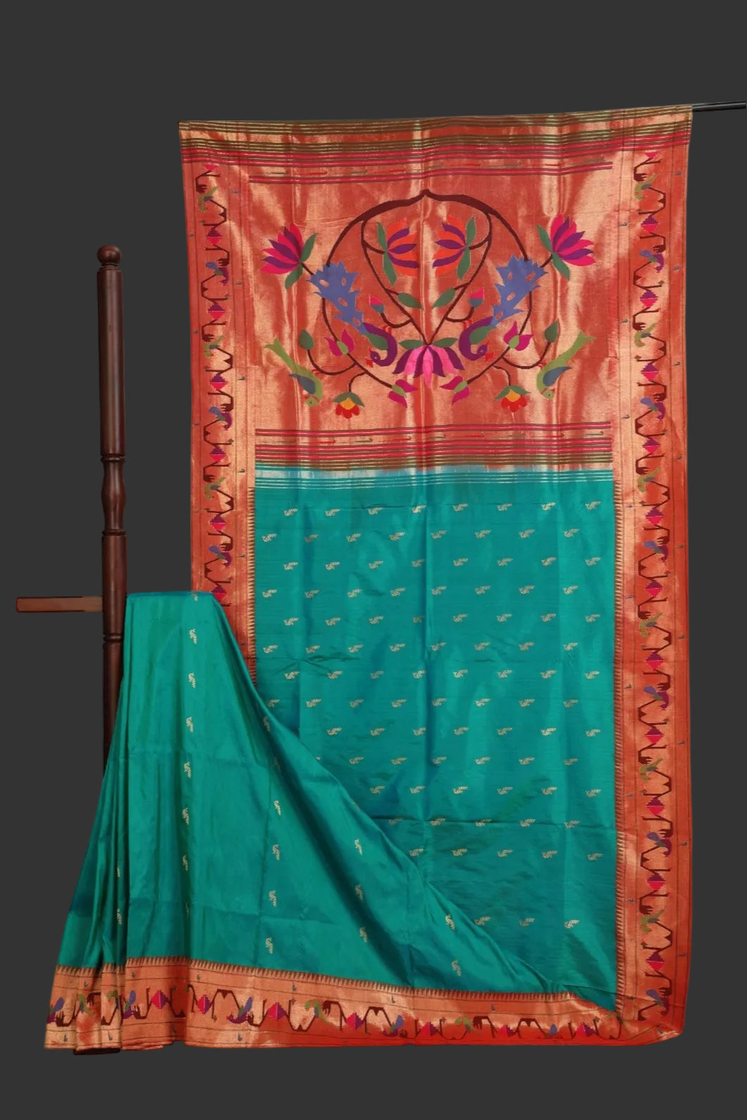 Teal saree with a red border featuring intricate patterns on a white background