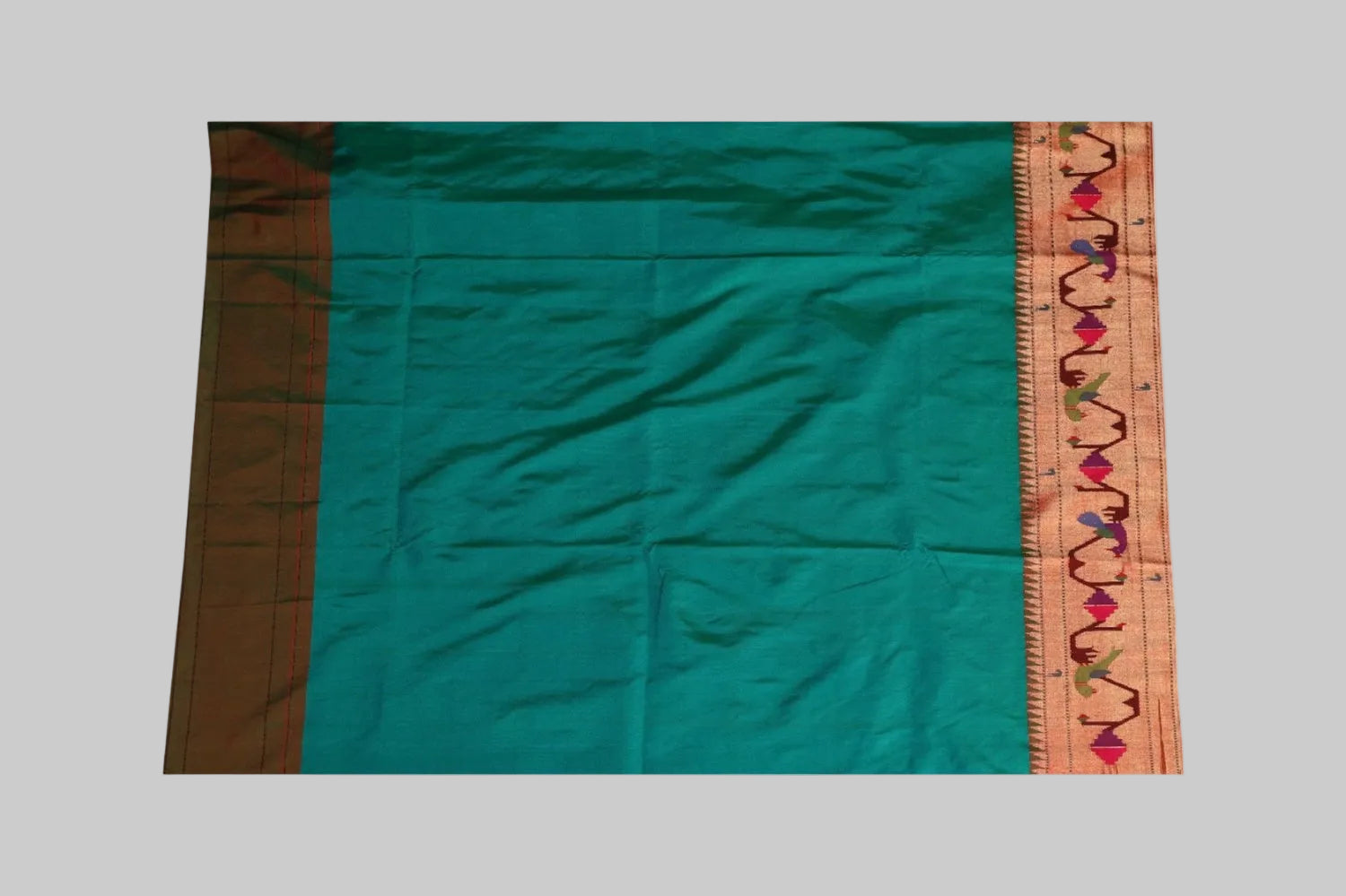 Teal saree with a decorative border on a white background
