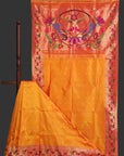 Orange saree with pink border and floral embroidery on a wooden stand.