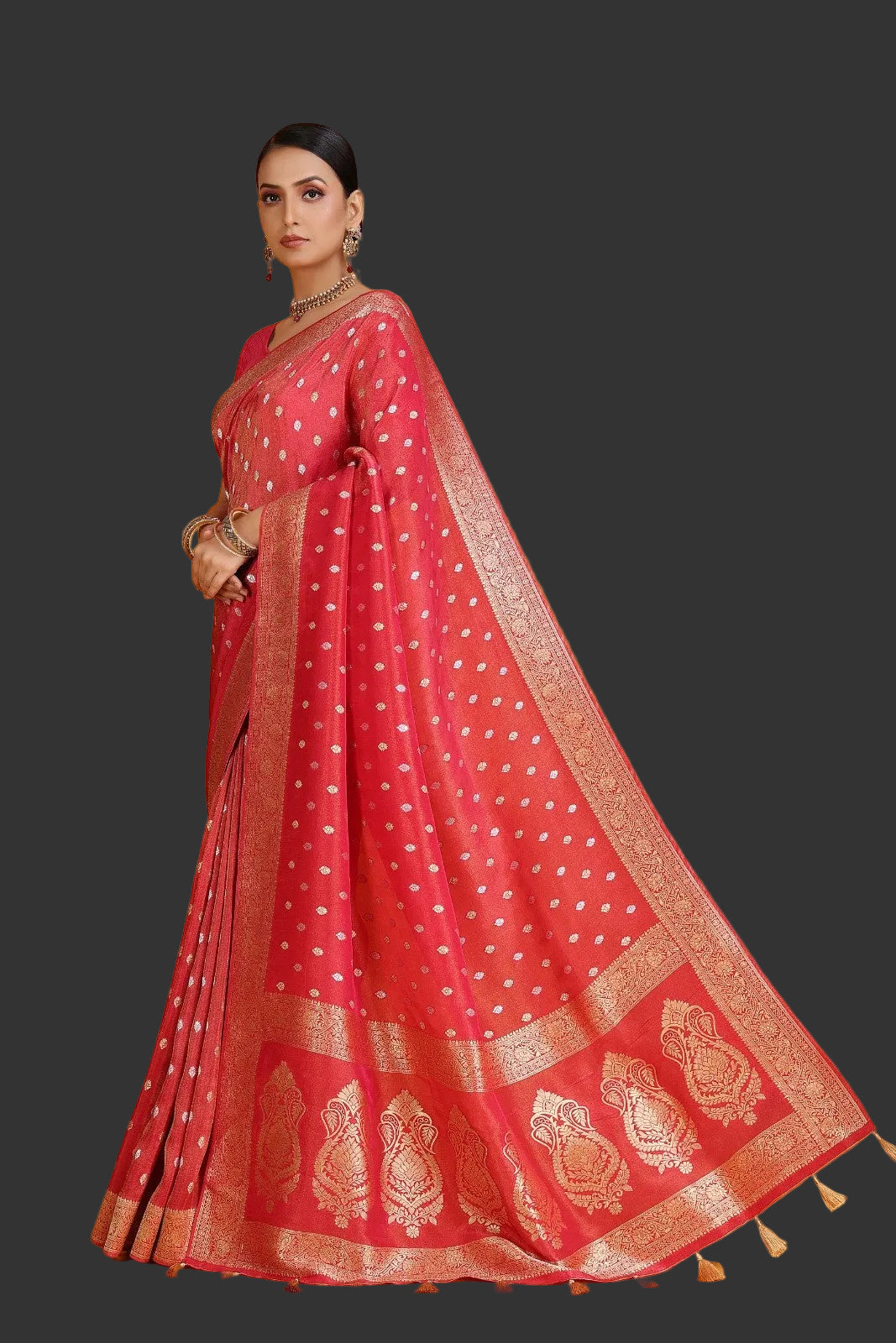 Woman wearing a red saree with gold patterns on an orange background