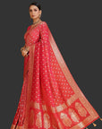 Woman wearing a red saree with gold patterns on an orange background