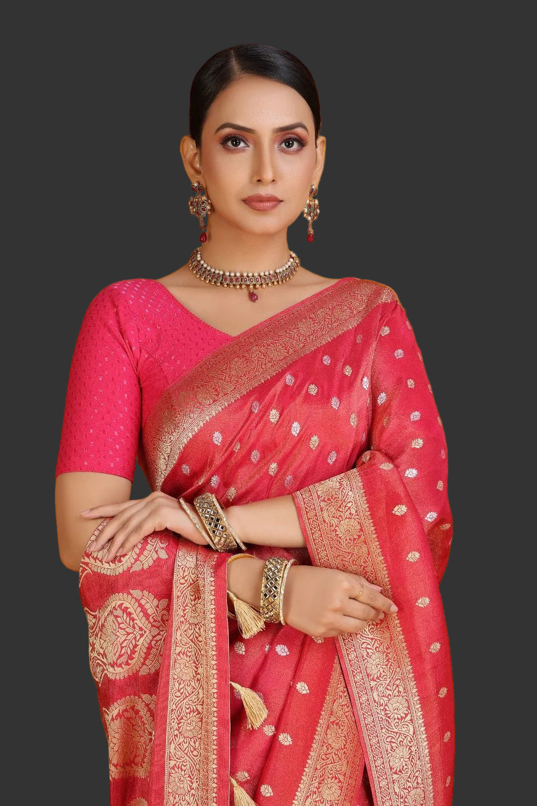 Woman wearing a pink saree with gold patterns on an orange background