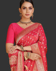 Woman wearing a pink saree with gold patterns on an orange background