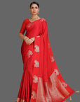Woman wearing a red saree with gold patterns on an orange background