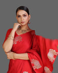 Woman wearing a red saree with elephant patterns on an orange background