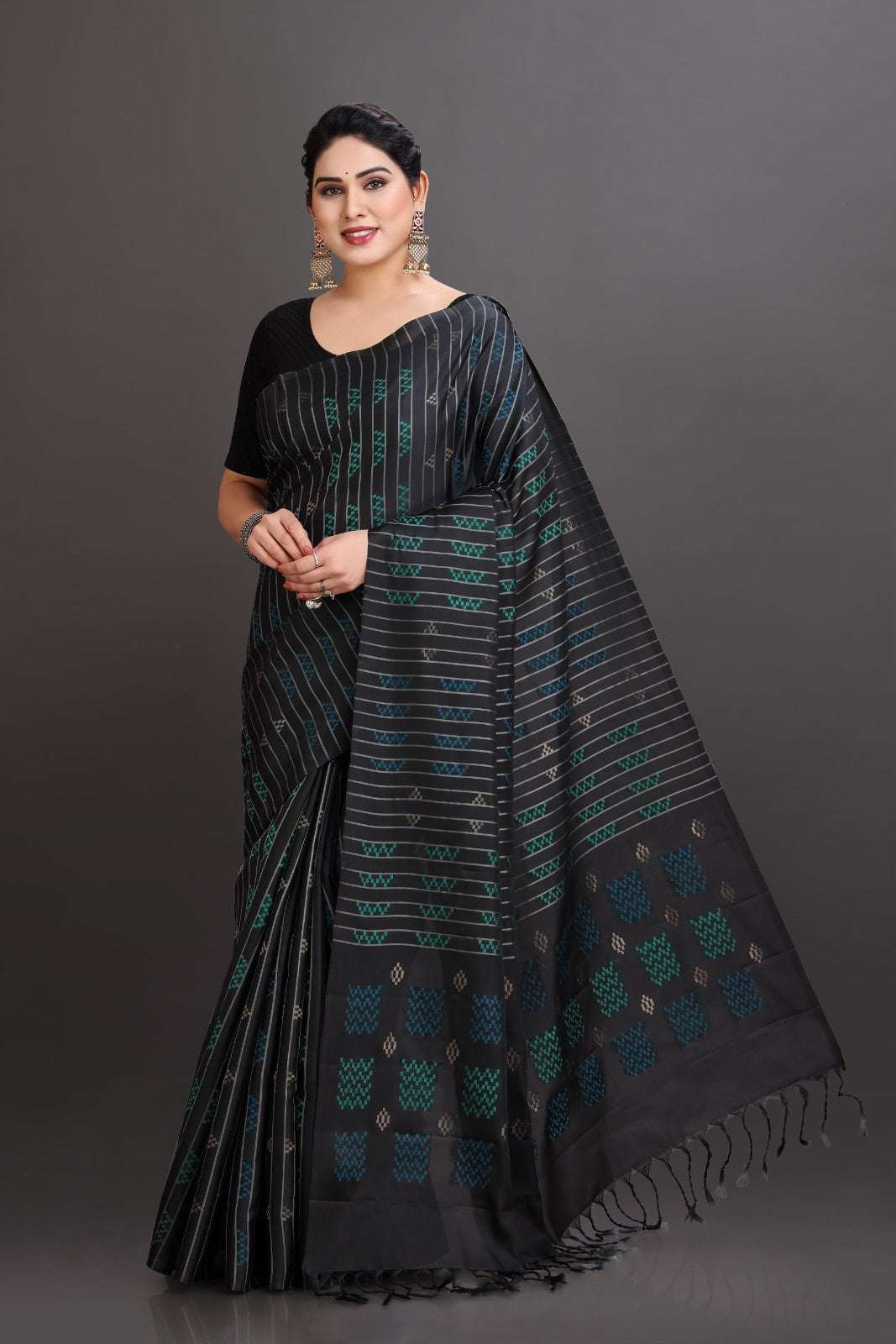 Woman wearing a black saree with green patterns on a gray background