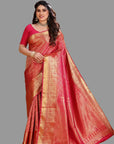 Woman wearing a red saree with gold patterns on an orange background
