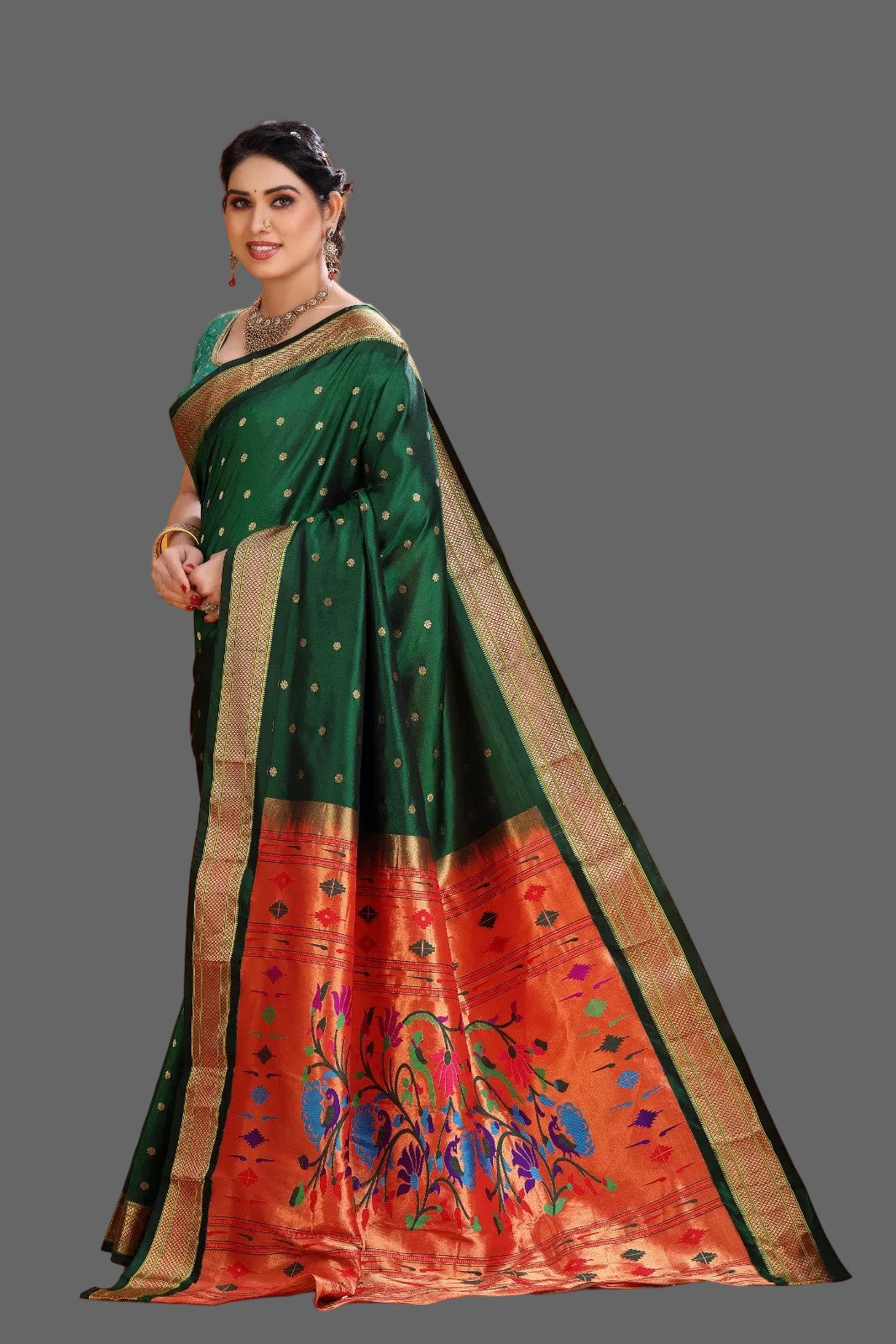 Woman wearing a green and red paithani saree with floral patterns on an orange background