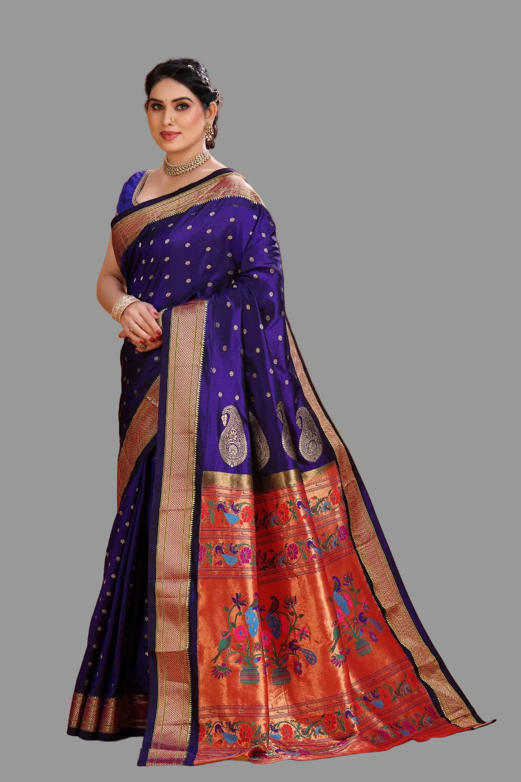 Woman wearing a traditional purple and orange paithani saree with intricate patterns on an orange background