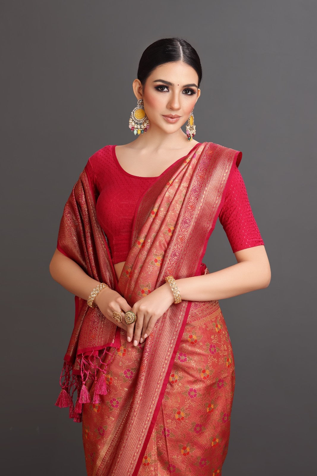 Woman wearing a red saree with a floral pattern on a gray background