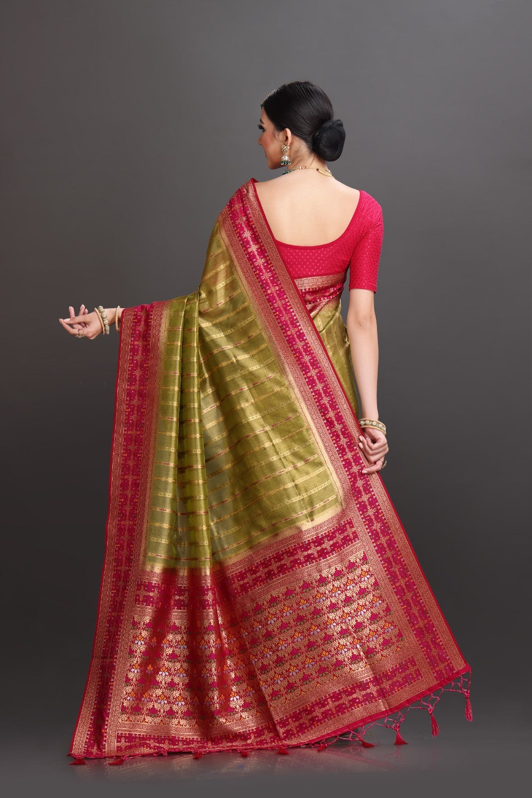 Woman wearing a green and red saree with a plain background