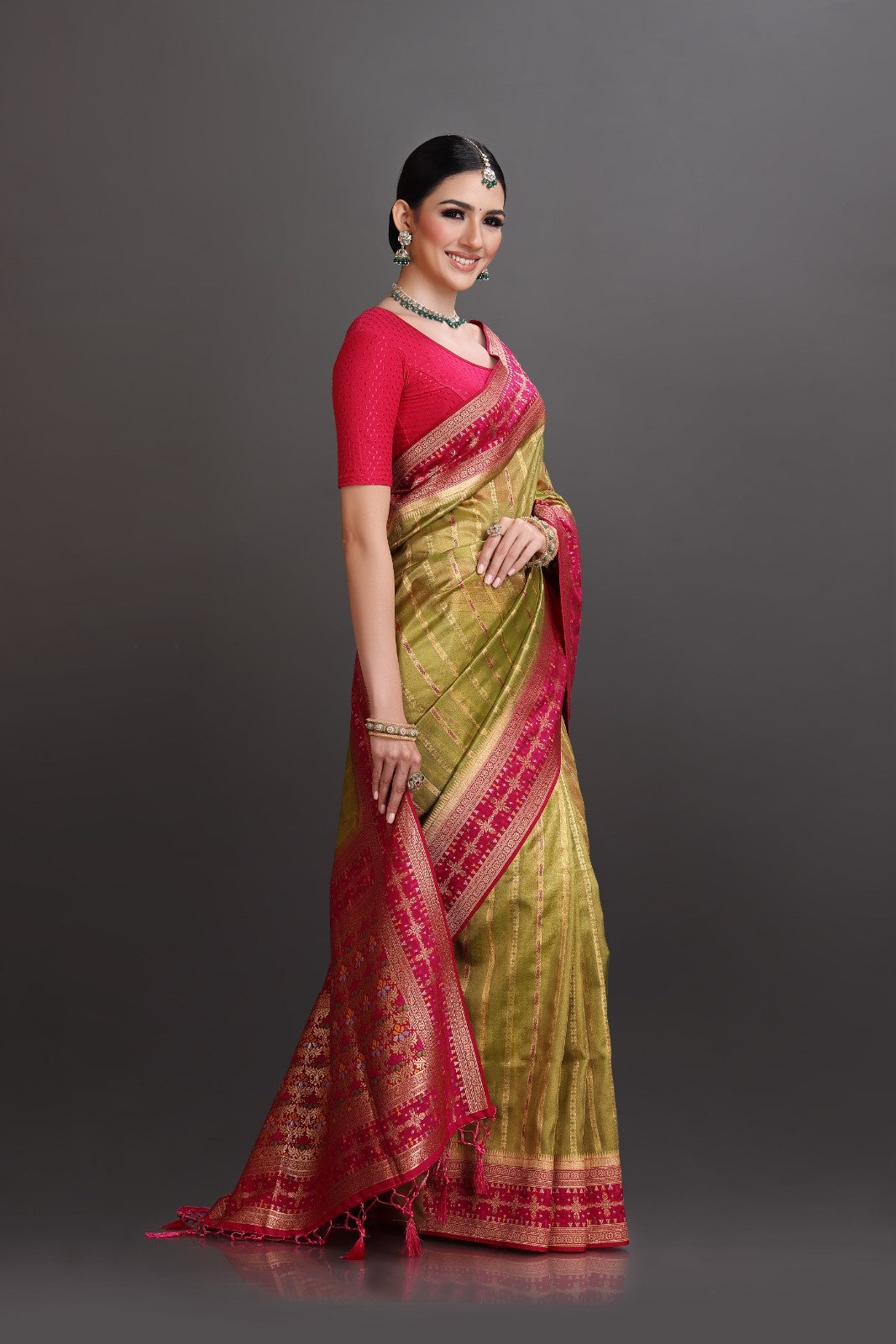 Woman wearing a green and red saree on a gray background
