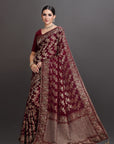 Woman wearing a maroon saree with floral patterns on a gray background