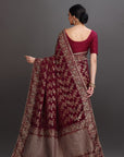 Woman wearing a traditional maroon and gray saree with a plain background