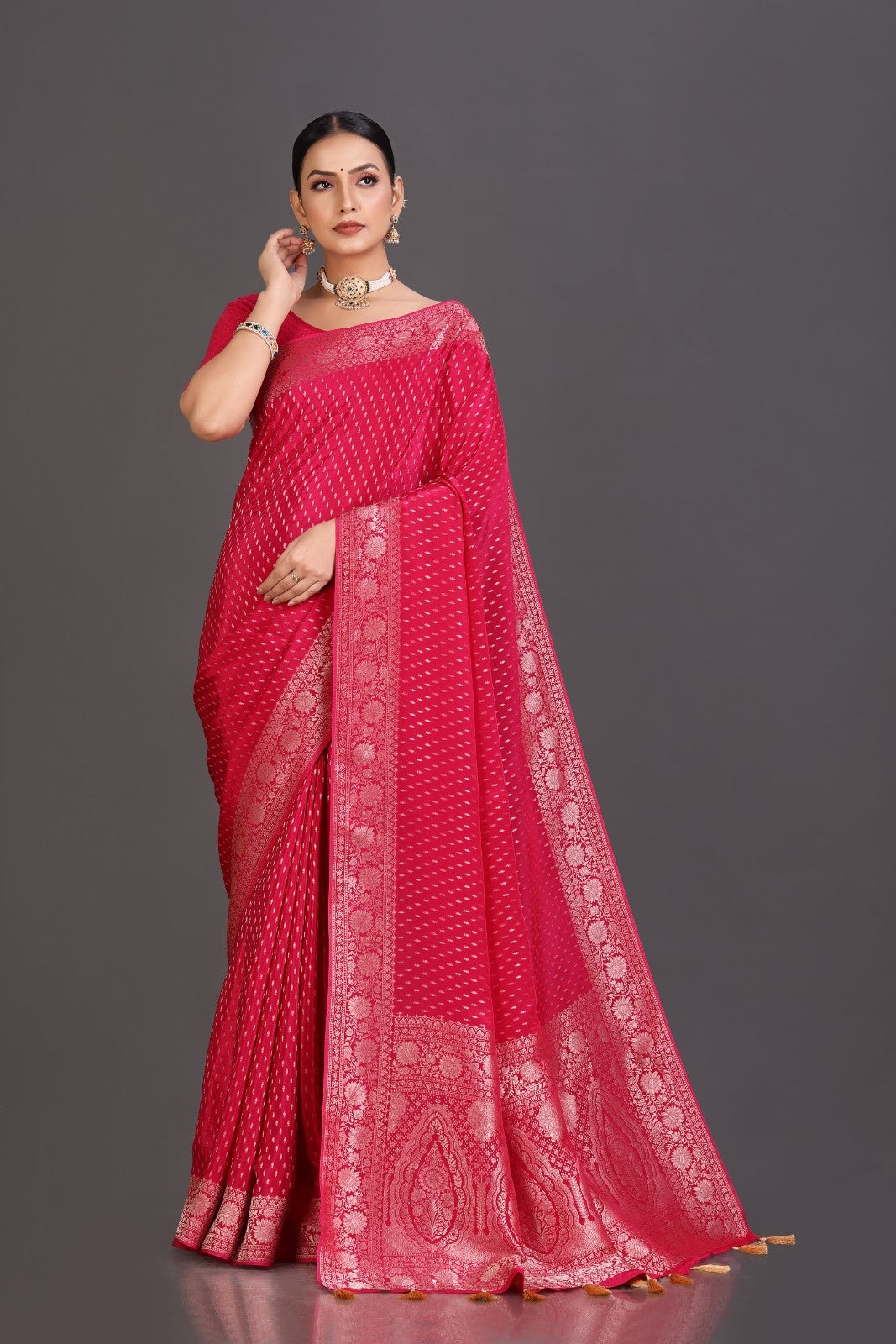 Woman wearing a red saree with white patterns on a gray background