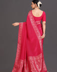 Woman wearing a bright pink saree with white patterns on a gray background