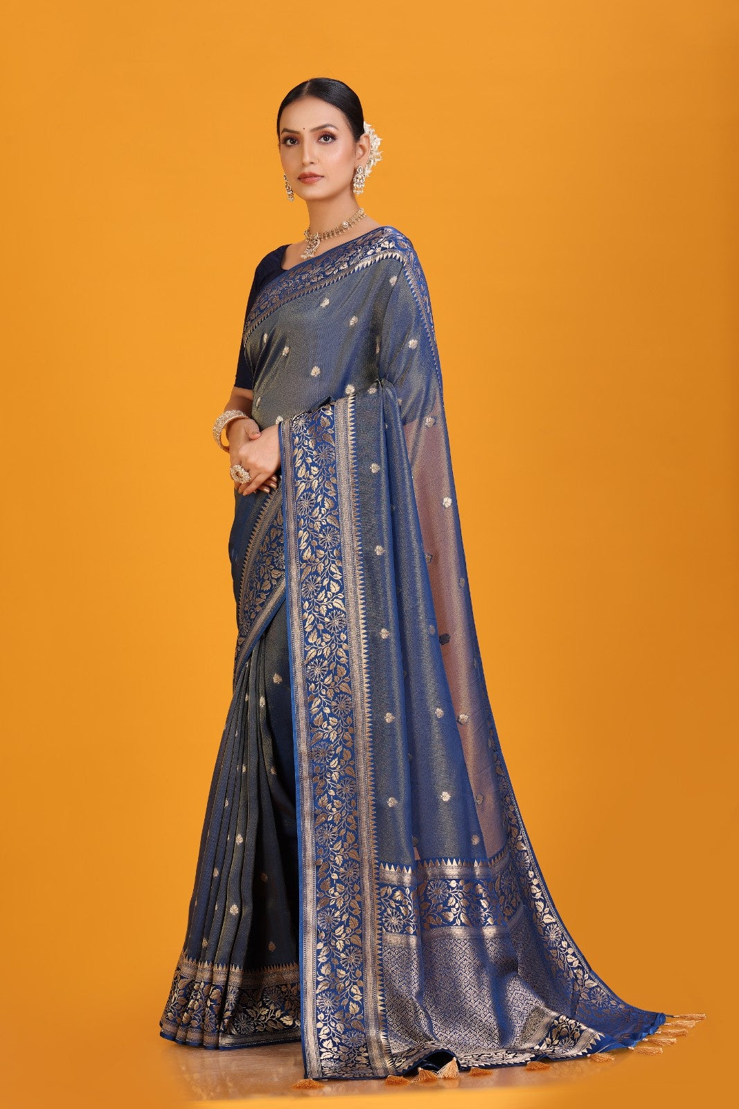 Woman wearing a blue saree with a gold border on an orange background