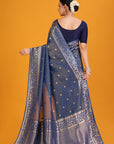 Woman wearing a blue saree with intricate patterns on an orange background