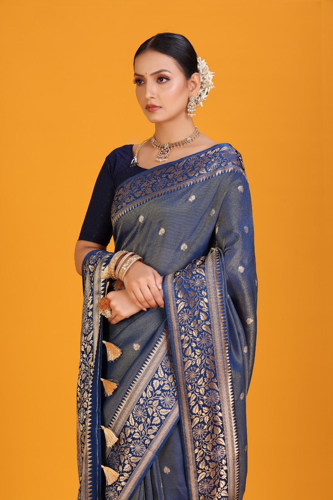 Woman wearing a blue saree with gold patterns on an orange background
