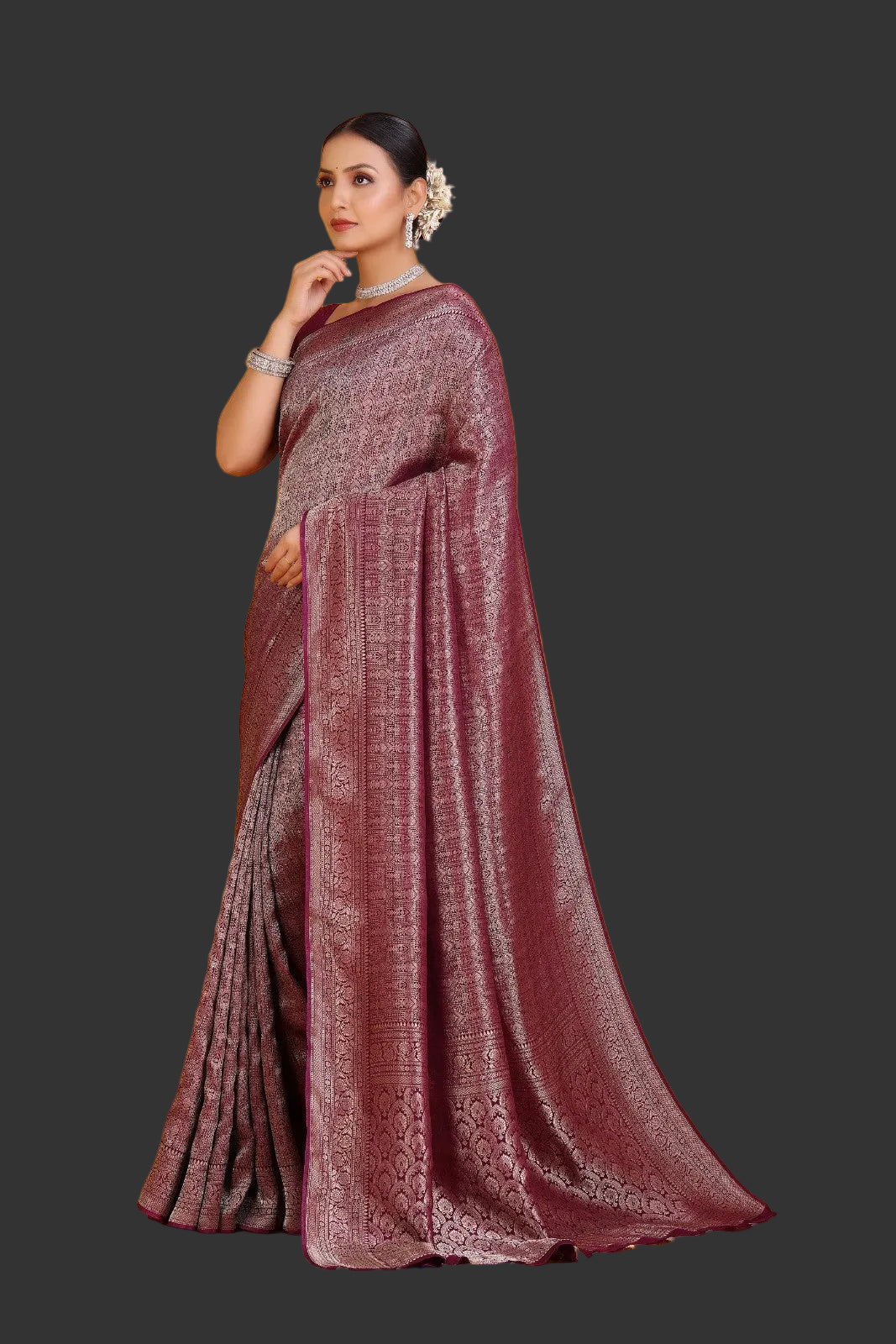 Woman wearing a maroon saree with a subtle pattern on an orange background
