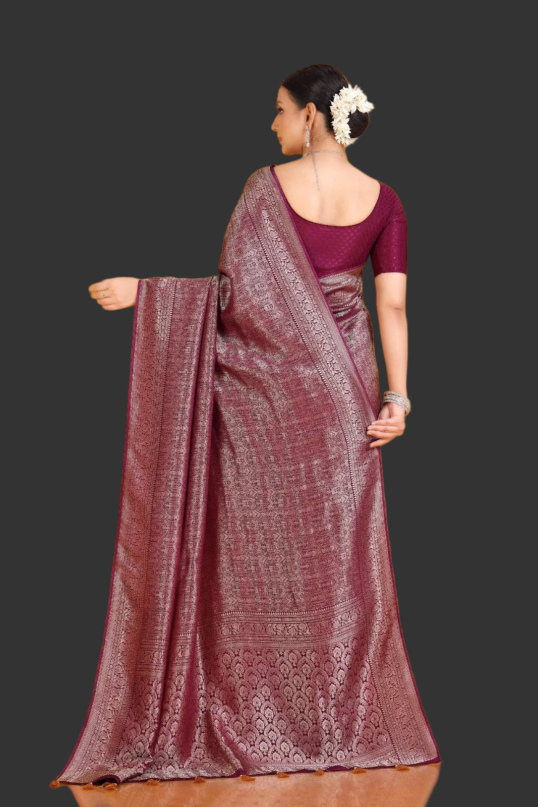 Woman wearing a maroon saree with a purple blouse against an orange background