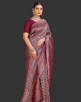 Woman wearing a maroon saree with a pattern on an orange background