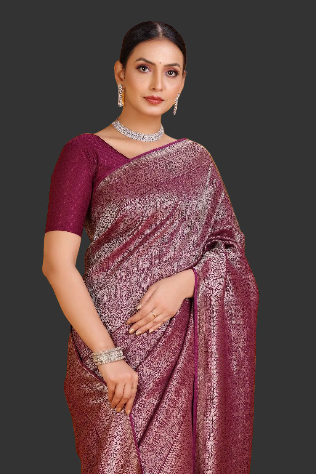 Woman wearing a maroon saree with a gold border on an orange background