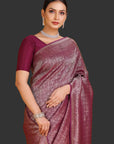 Woman wearing a maroon saree with a gold border on an orange background
