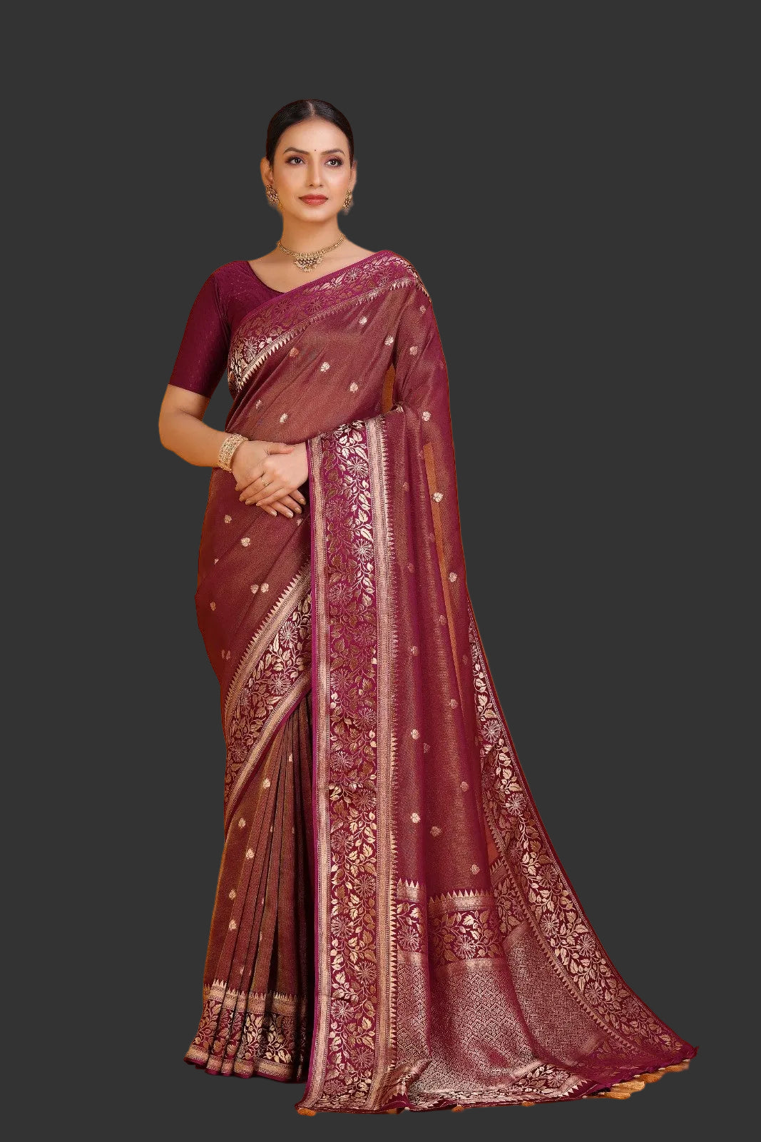 Woman wearing a maroon saree with gold patterns on an orange background