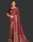 Woman wearing a maroon saree with gold patterns on an orange background