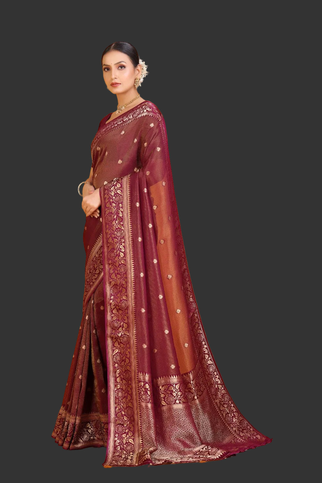 Woman wearing a maroon saree with gold patterns on an orange background